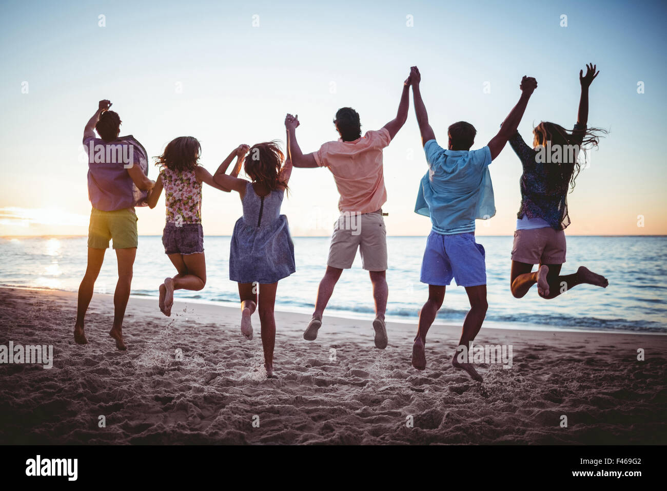 Happy friends holding hands and jumping Stock Photo Alamy