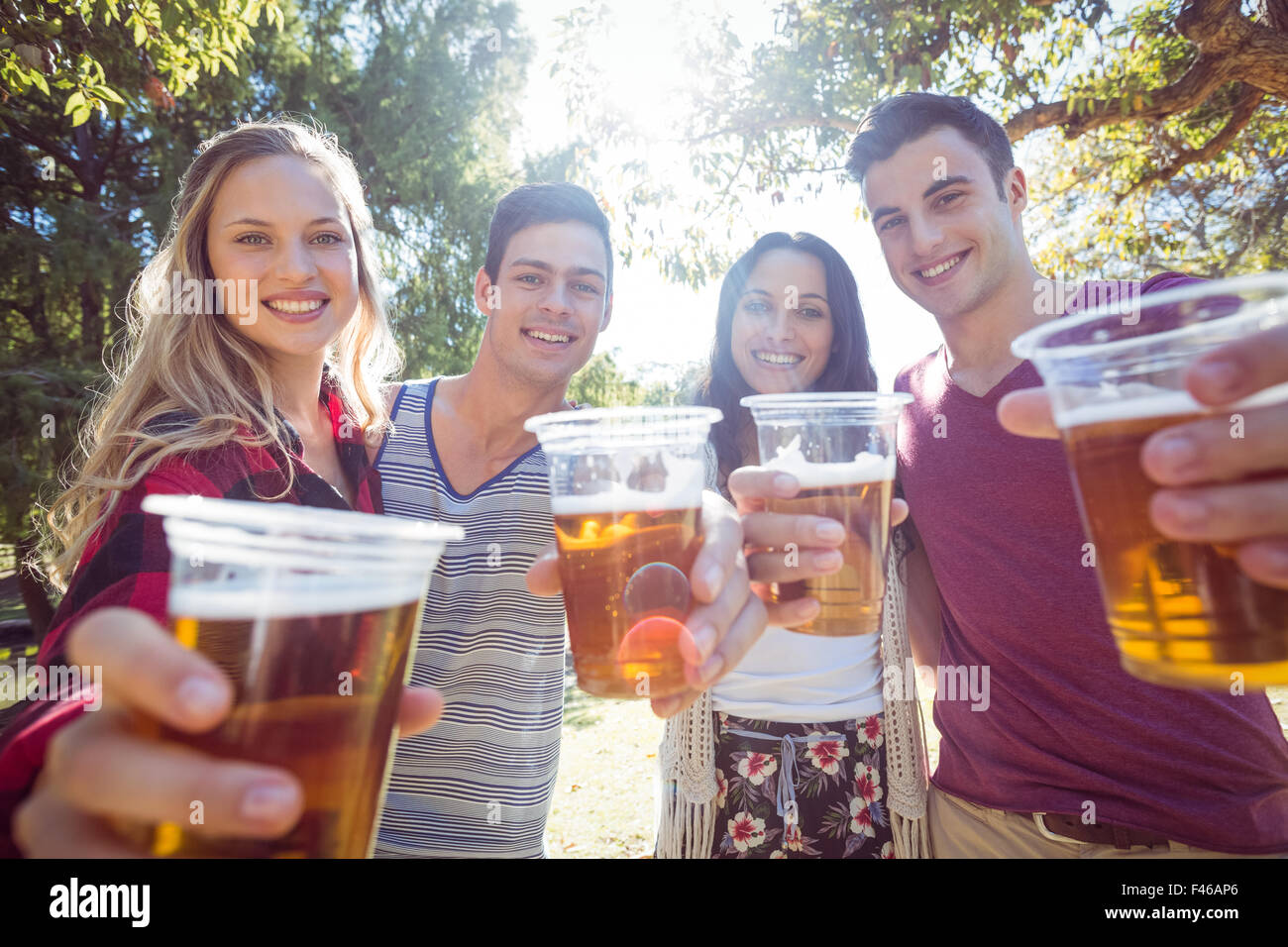 Happy friends in the park having beers Stock Photo - Alamy