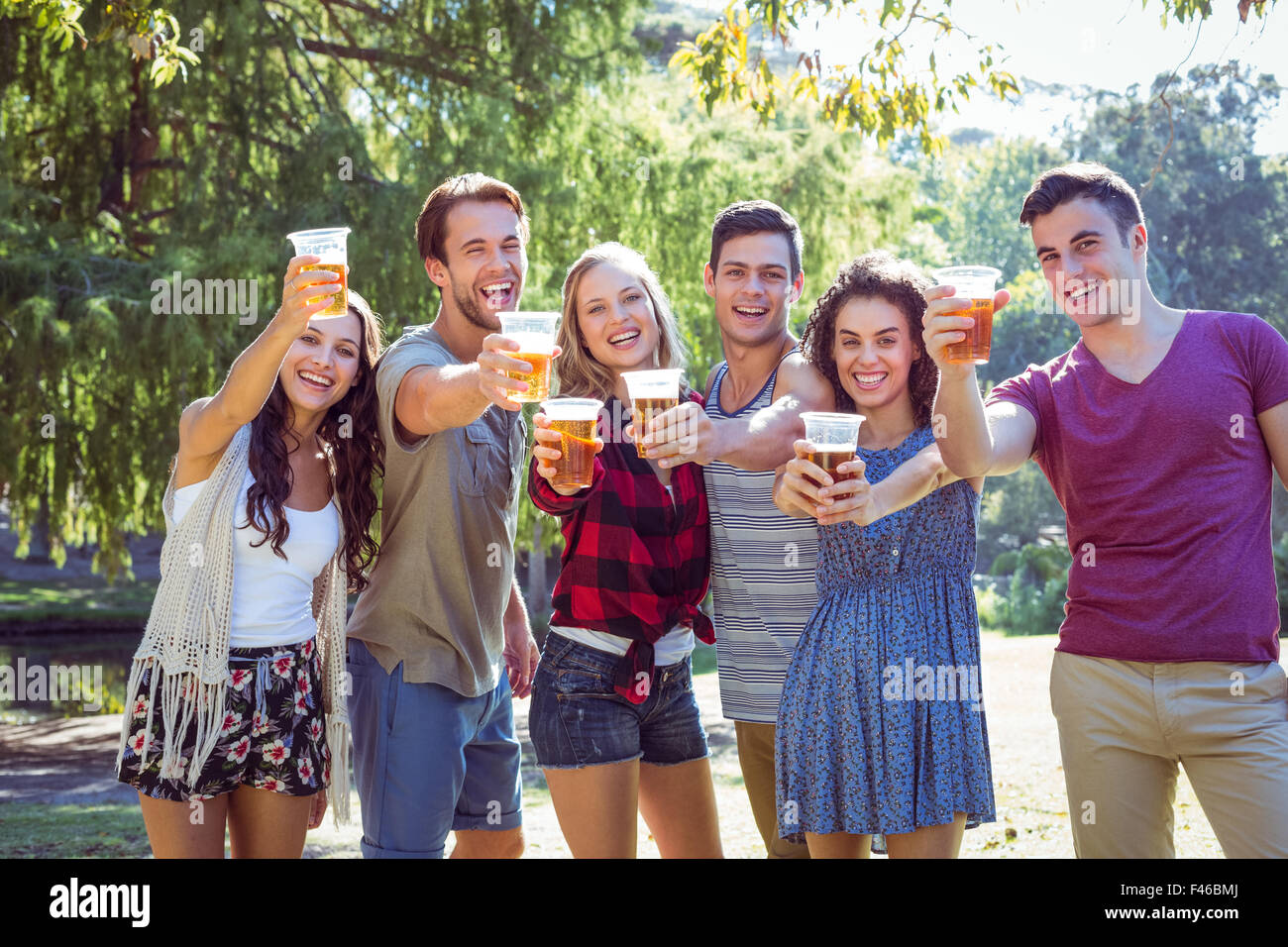 Happy friends in the park having beers Stock Photo - Alamy