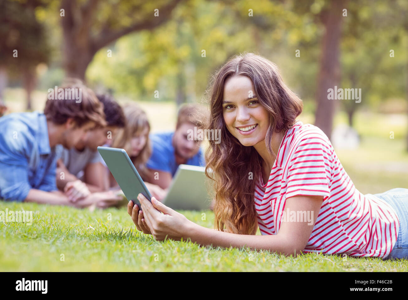 Pretty brunette using tablet in the park Stock Photo - Alamy
