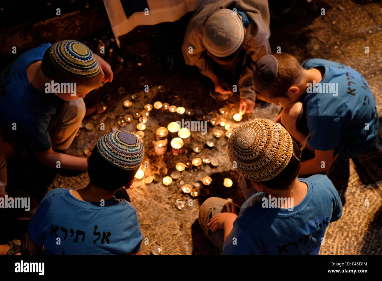 ISRAEL - JERUSALEM 09 OCTOBER 2015: Religious Jewish children light memorial candles as their parents pray in Hagai street in the Muslim Quarter Old city of Jerusalem, Israel on October 8, 2015. Hagai street a main commercial street in the old city has been the site of recent attacks from Palestinians. Stock Photo