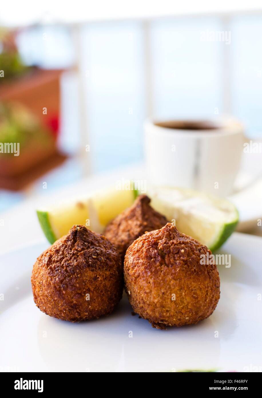 Three small pieces of kebbe, a lebanese dish with mince meat or mushrooms and lemon and coffee on the background. Delicious food Stock Photo