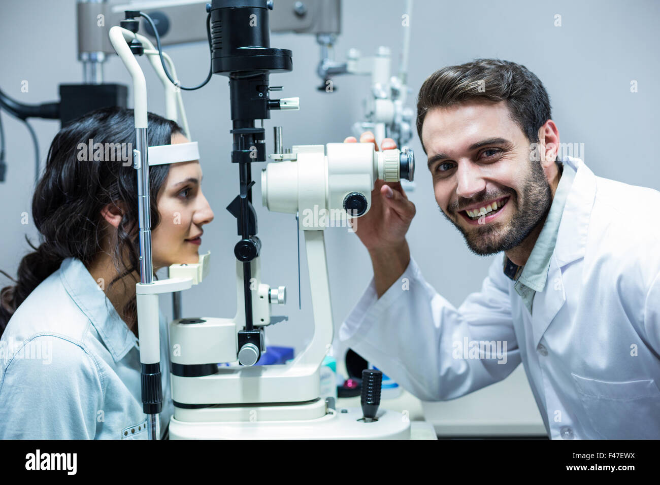 Happy optician and female patient with slit lamp Stock Photo