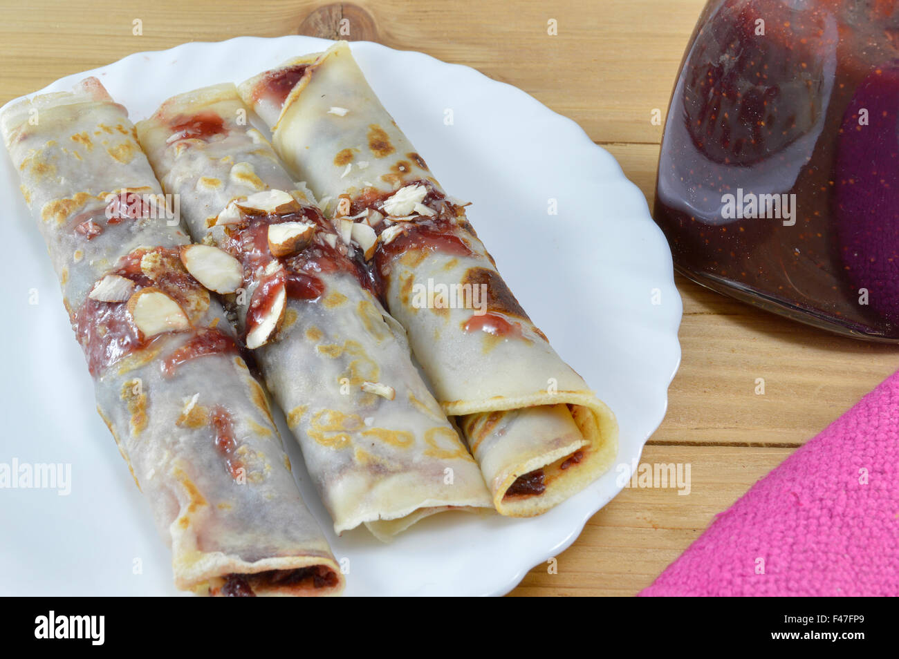 Sweet pancakes with strawberry jam and hazelnuts served on the plate Stock Photo