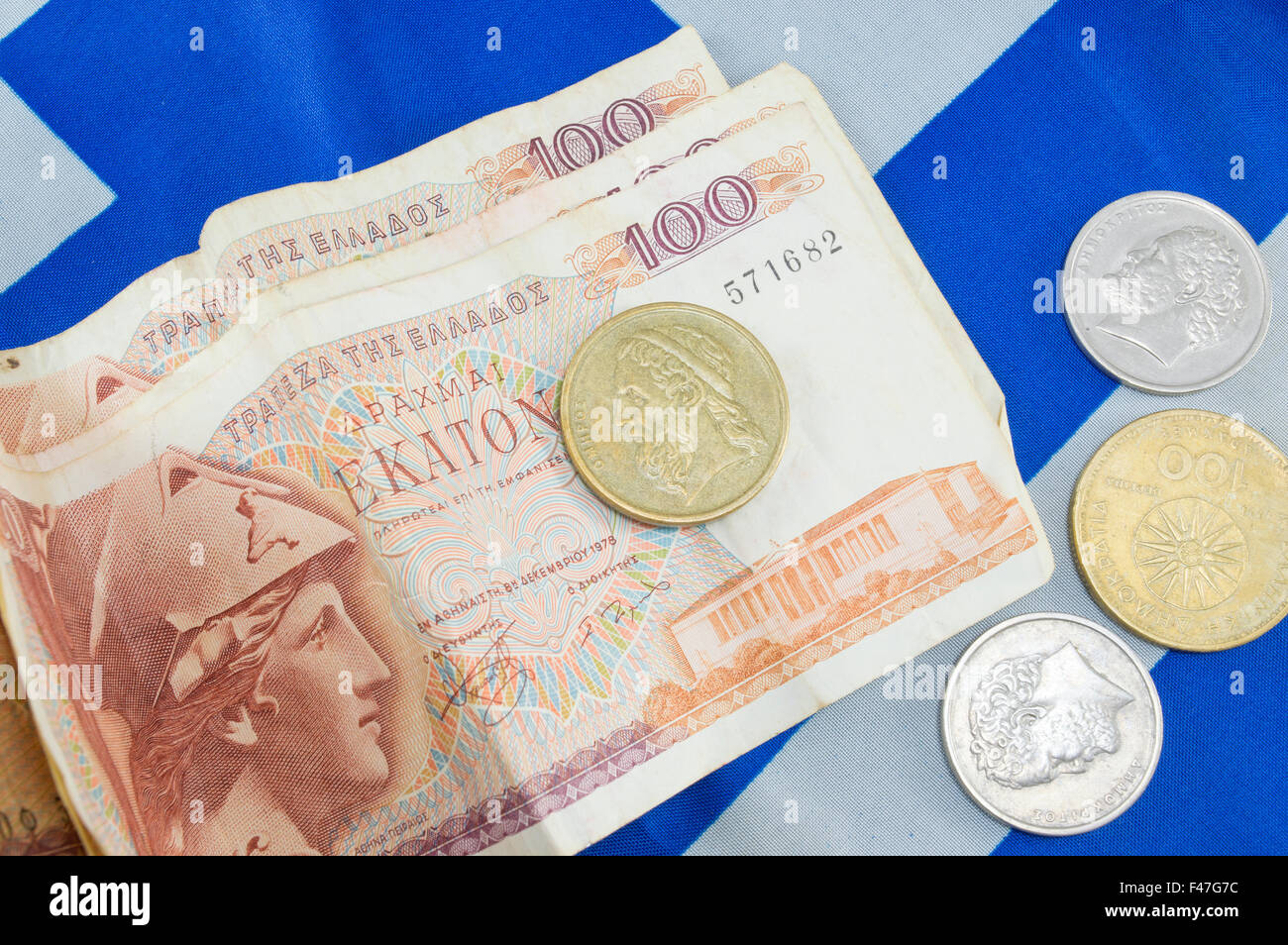 Greek old currency drachma banknotes piled on the Greek flag Stock Photo