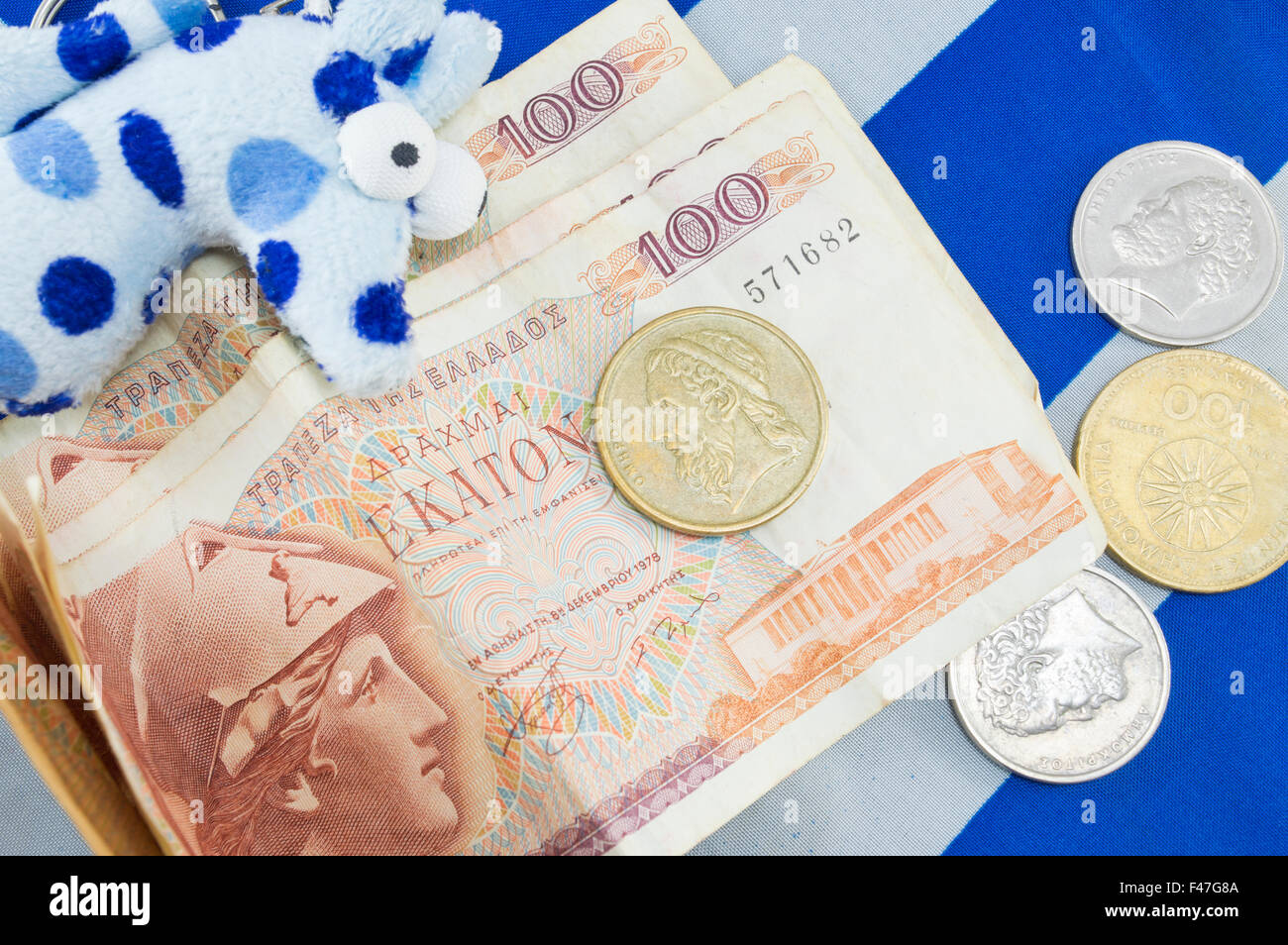 Greek old currency drachma banknotes piled on the Greek flag Stock Photo