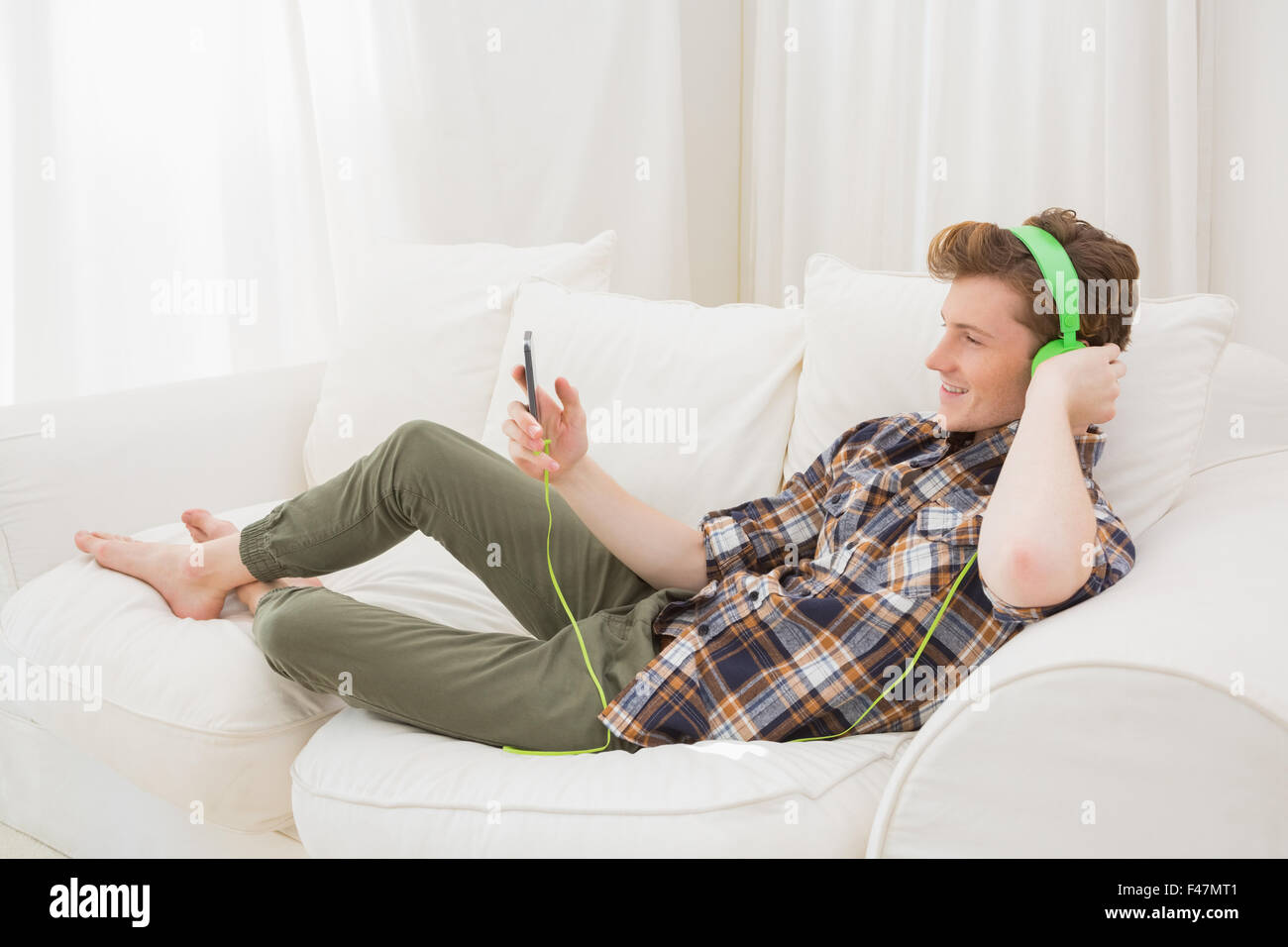 Handsome man listening music with headphone on sofa Stock Photo - Alamy