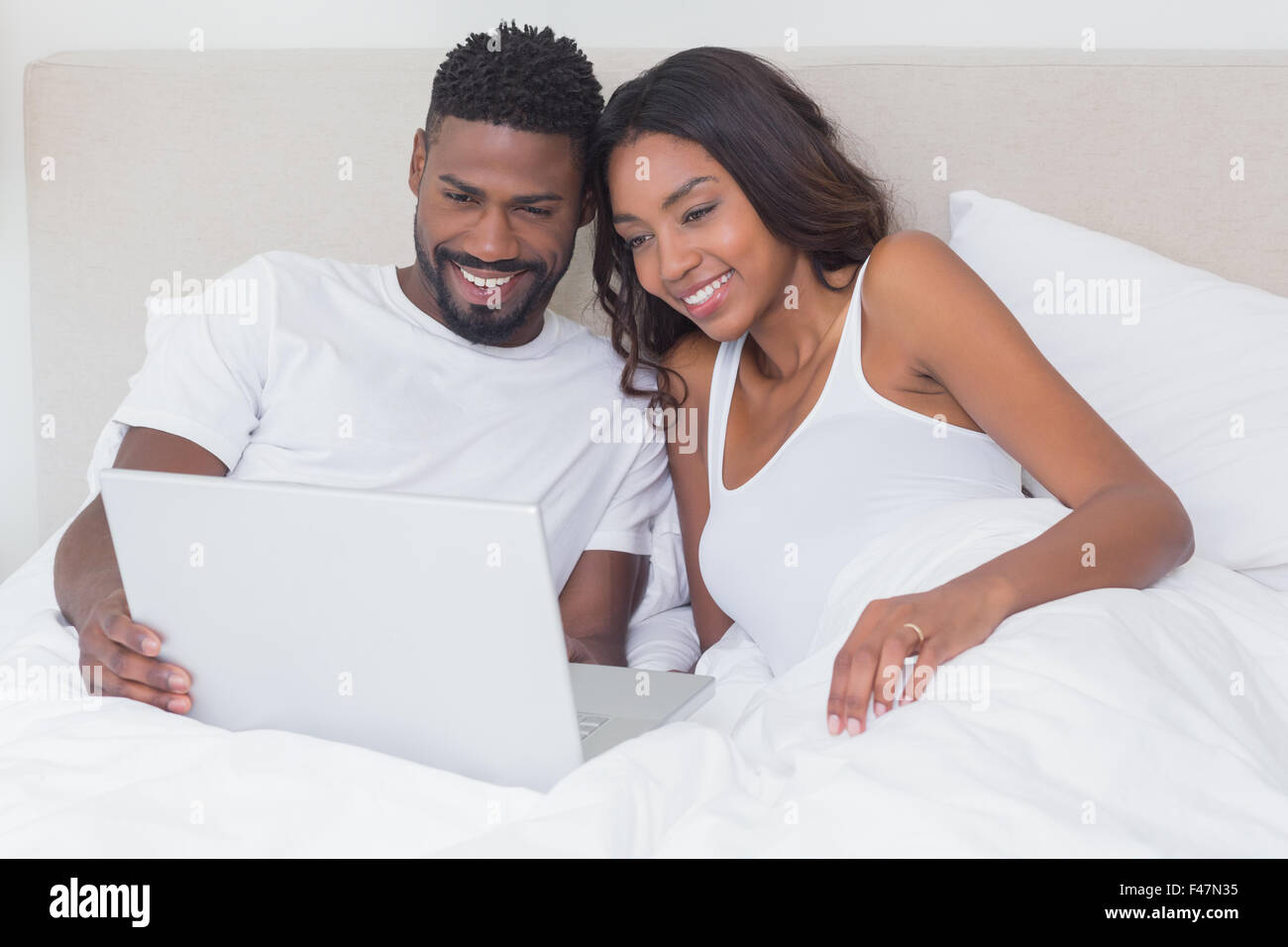 Relaxed couple using laptop in bed together Stock Photo - Alamy