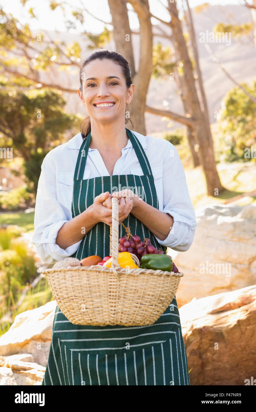 Cheerful woman holding basket of vegetables Stock Photo - Alamy