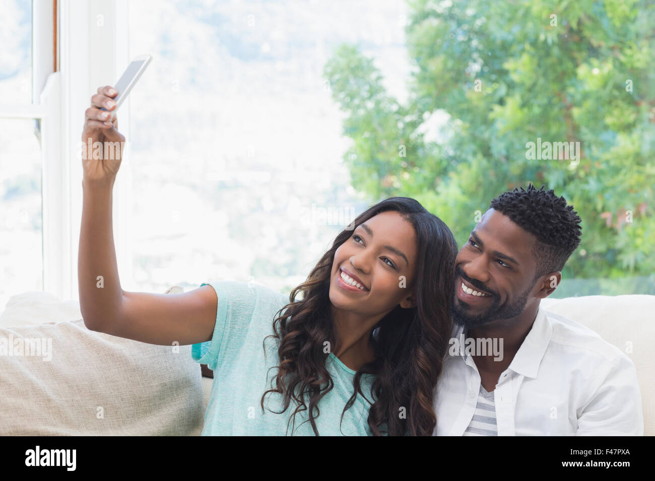 Happy couple on the couch taking selfie Stock Photo - Alamy