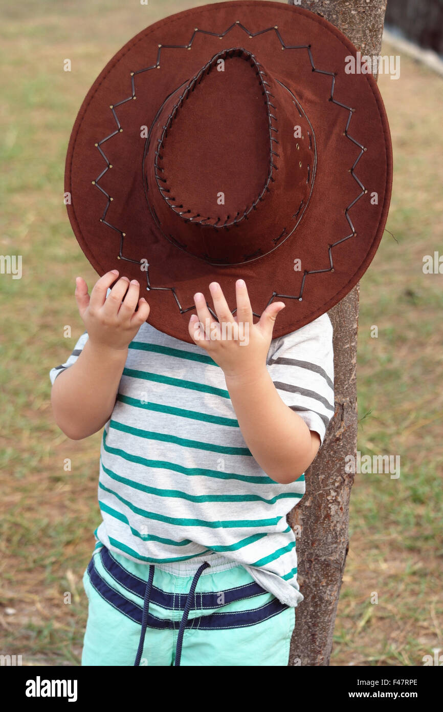 kid covering his face using cowboy hat. Stock Photo