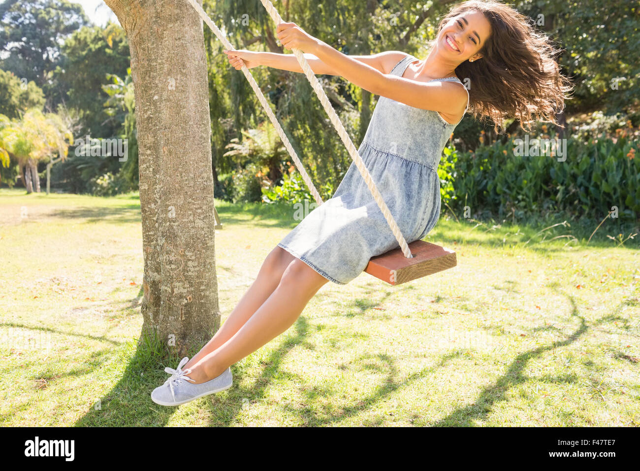 Pretty brunette swinging in park Stock Photo - Alamy