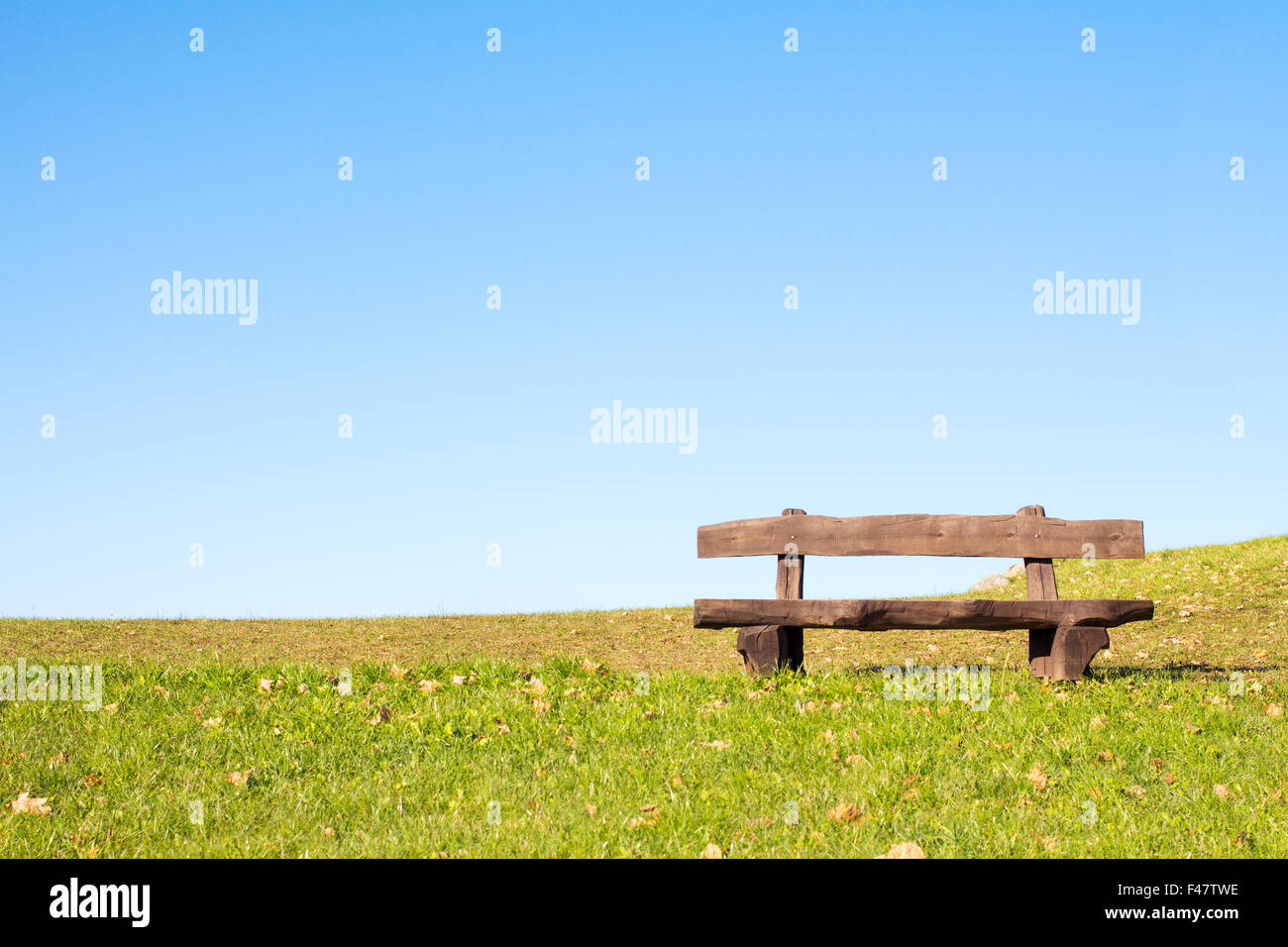 A calm place to rest and relax. An empty wooden bench  over a serene blue sky waiting for a hiker or casual walker to sit and re Stock Photo