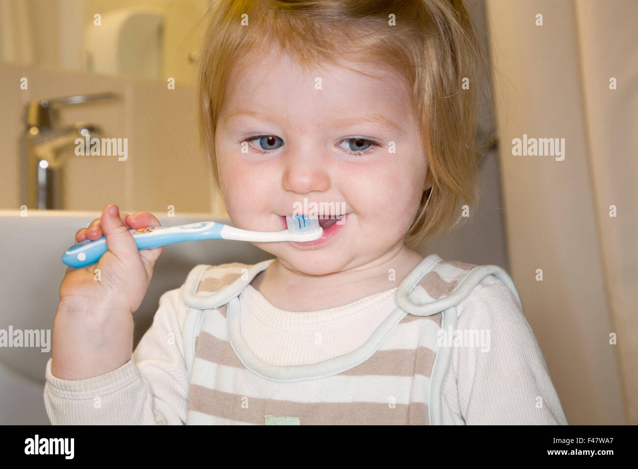 Child / baby practising brushing her teeth with a toothbrush / tooth brush for the first time
