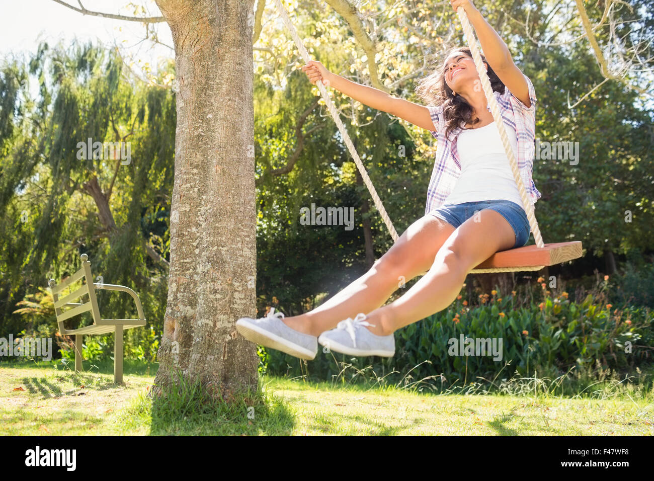 Pretty brunette swinging in park Stock Photo - Alamy