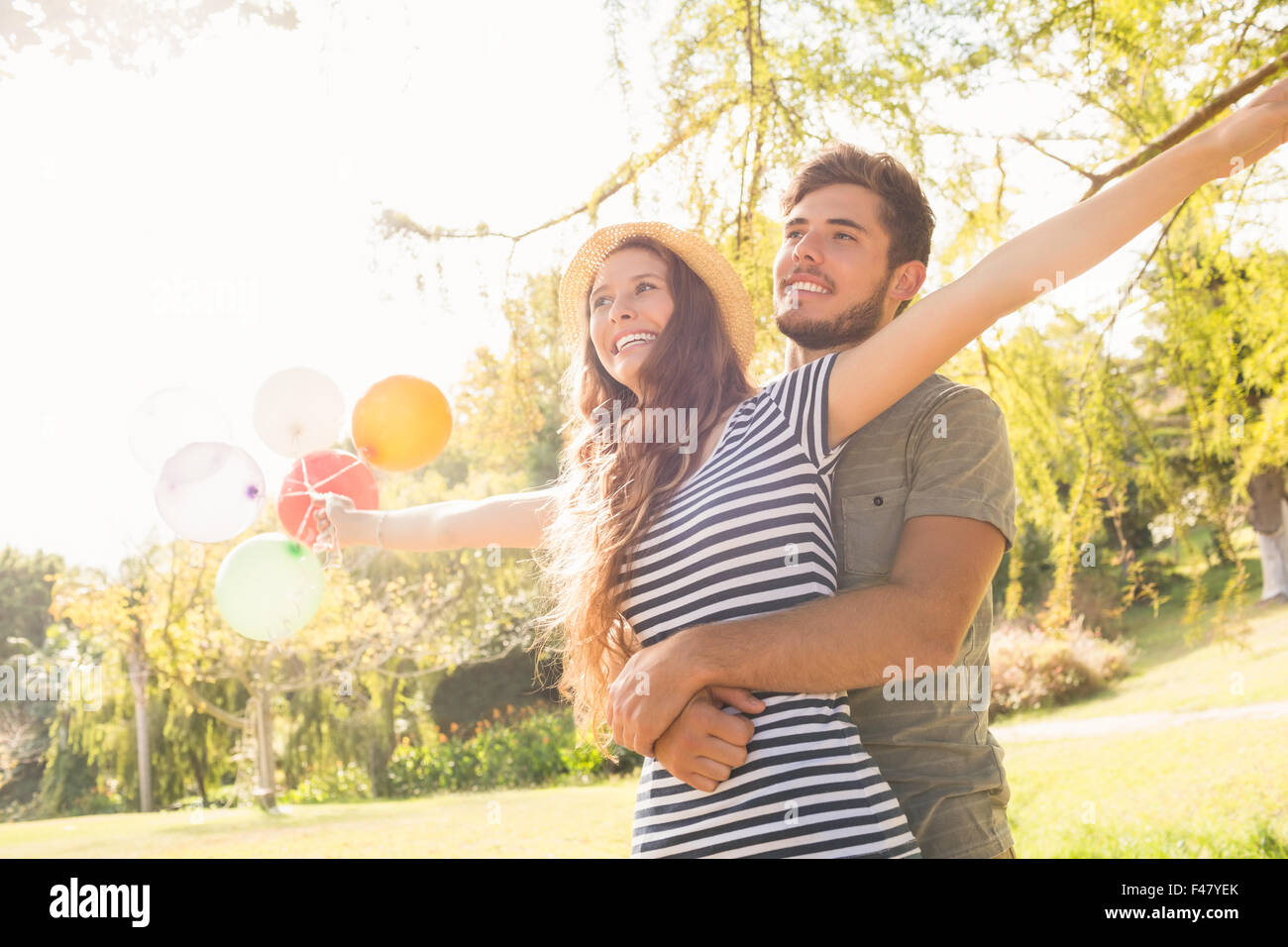 Cute couple hugging and holding balloons in the park Stock Photo - Alamy