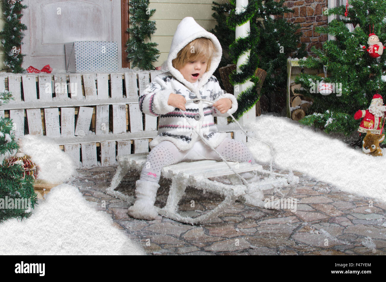 child on sled in yard of winter snow Stock Photo