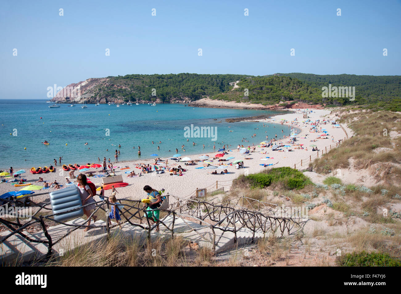 Tourists crowd the beautiful sandy beach of Algaiarens on the island of Menorca Spain Stock Photo