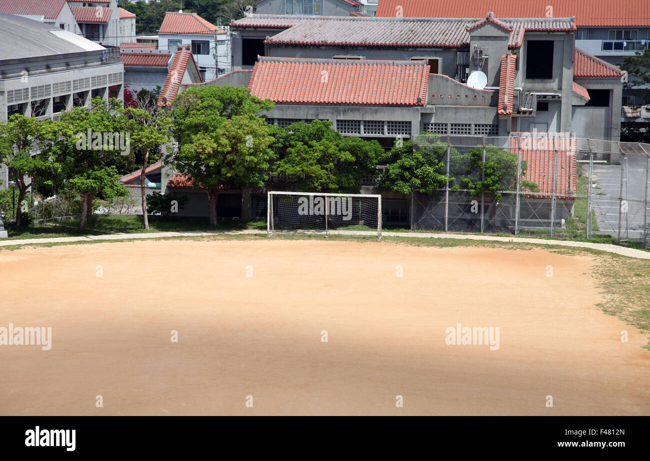 It's a photo of a football field or soccer field in a city near houses. It's in dry dusty earth. Nobody plays Stock Photo