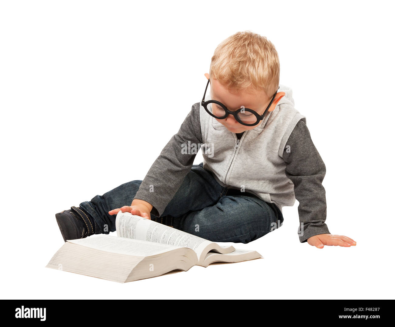 little child try to reading a book with funny glasses Stock Photo