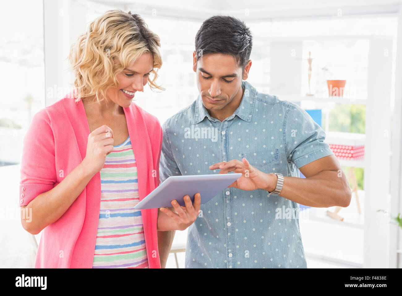 Colleagues standing and using tablet computer together Stock Photo