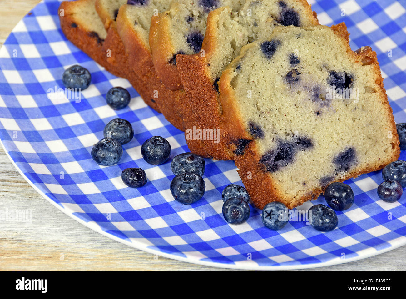 Sliced blueberry bread with ripe blueberries on blue and white checkered plate. Stock Photo