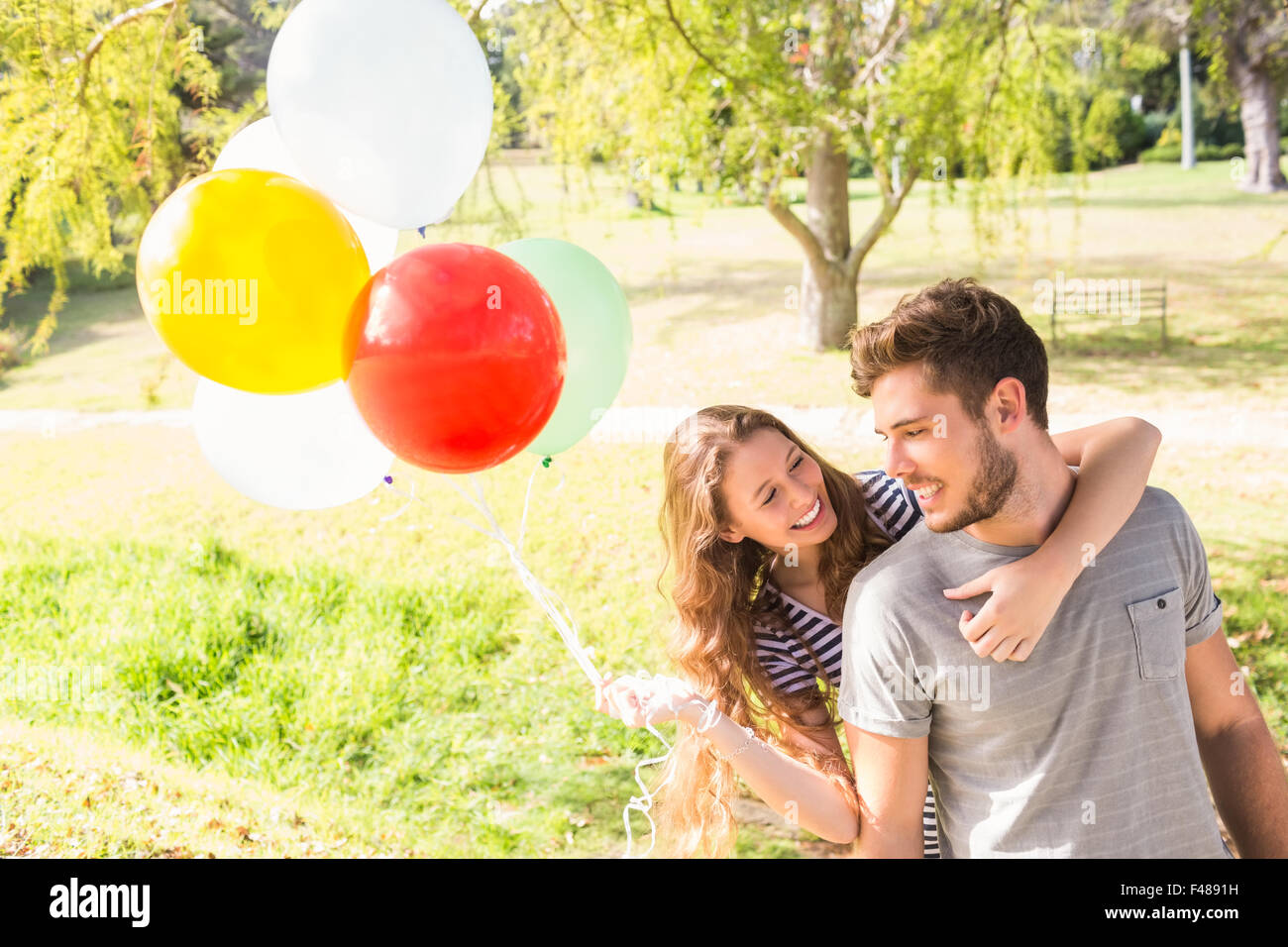 Cute couple holding balloons in the park Stock Photo - Alamy