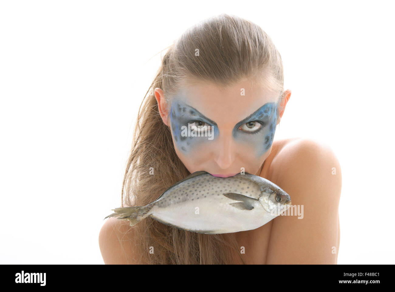 Woman in make-up with fish in mouth Stock Photo