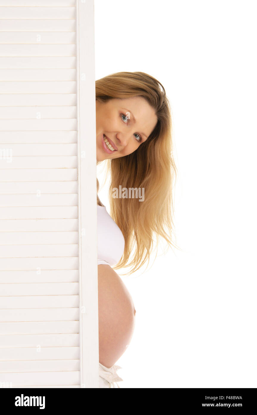 pregnant woman peeping from behind the door Stock Photo