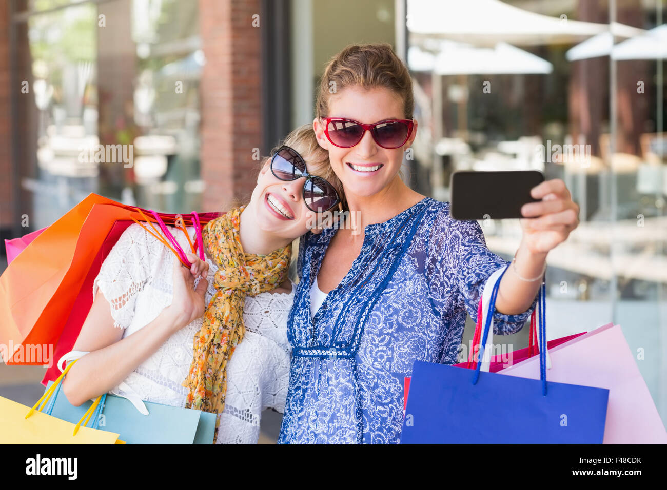 Beautiful women holding shopping bags making a selfie Stock Photo - Alamy
