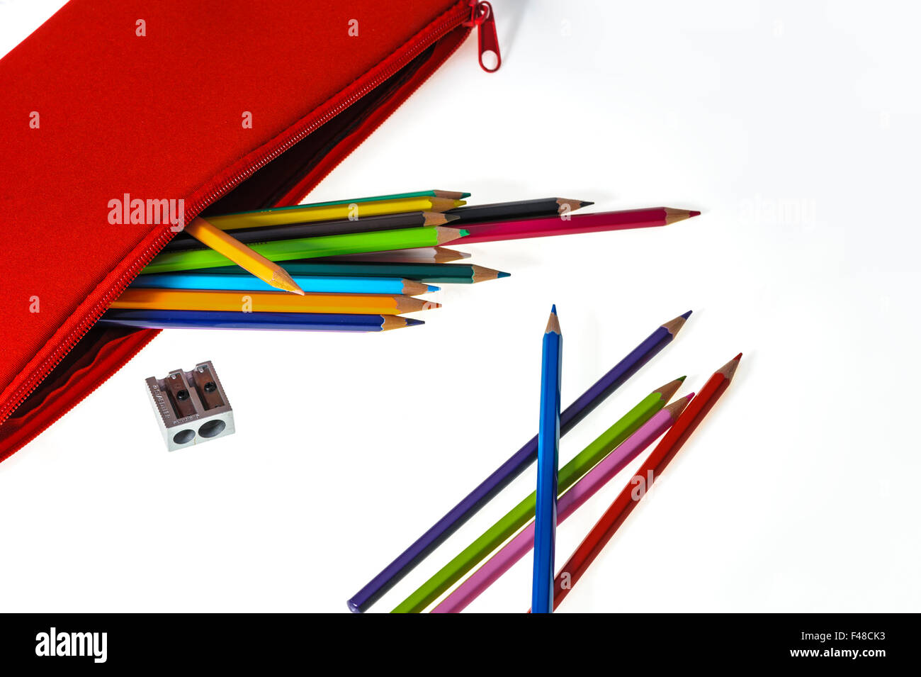 Red pencil case with coloured pencils and sharpener. Stock Photo