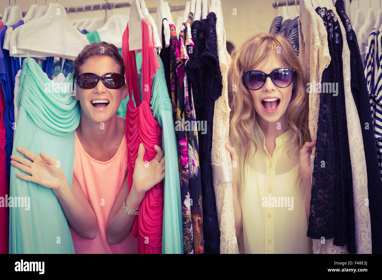 Friends wearing sunglasses between clothes racks Stock Photo - Alamy