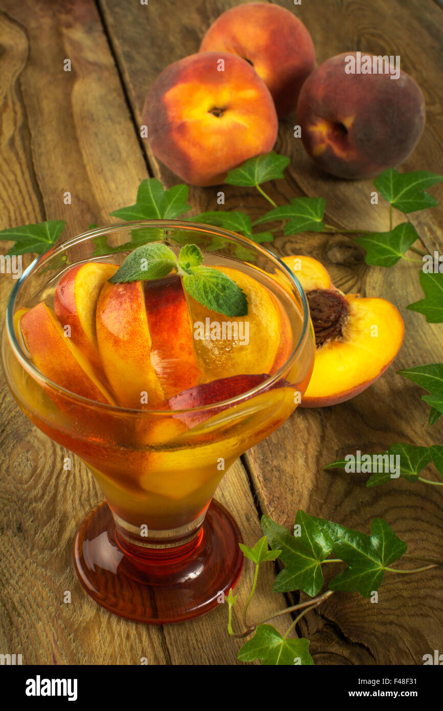 Peach drink in glass on a wooden background with peaches and ivy branch. Selective focus. The toning Stock Photo