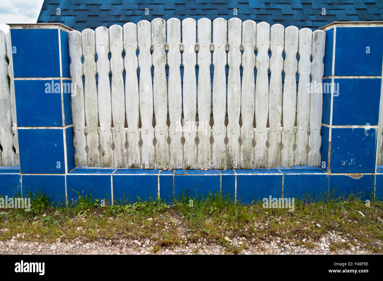 Old white fence with colorful blue tile. Stock Photo