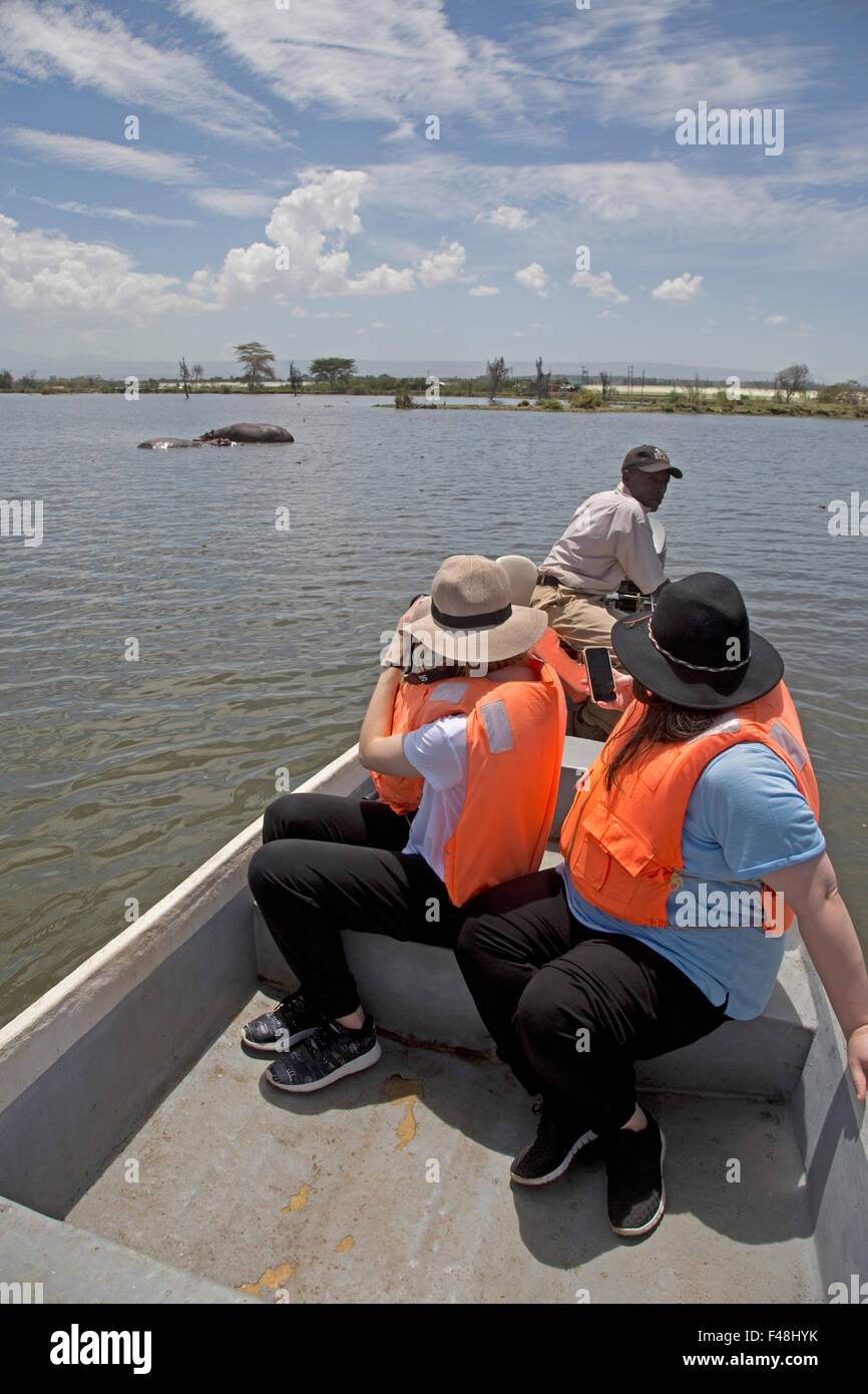 Women tourists in boat watching hippo Lake Naivasha Kenya Stock Photo