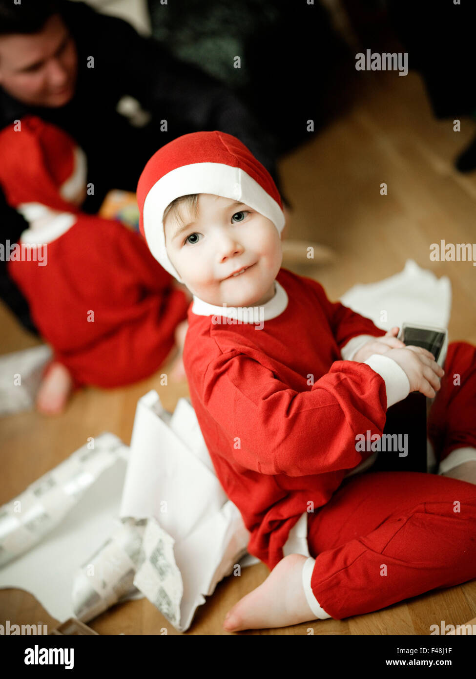 Boy dressed as Santa Claus opening Christmas presents, Sweden. Stock Photo