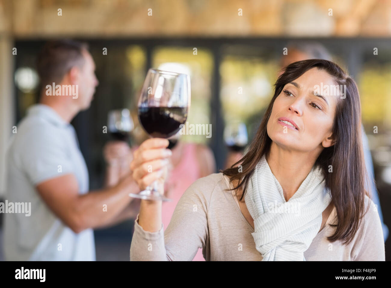 Brunette woman looking at wine in front of group doing wine tasting Stock Photo