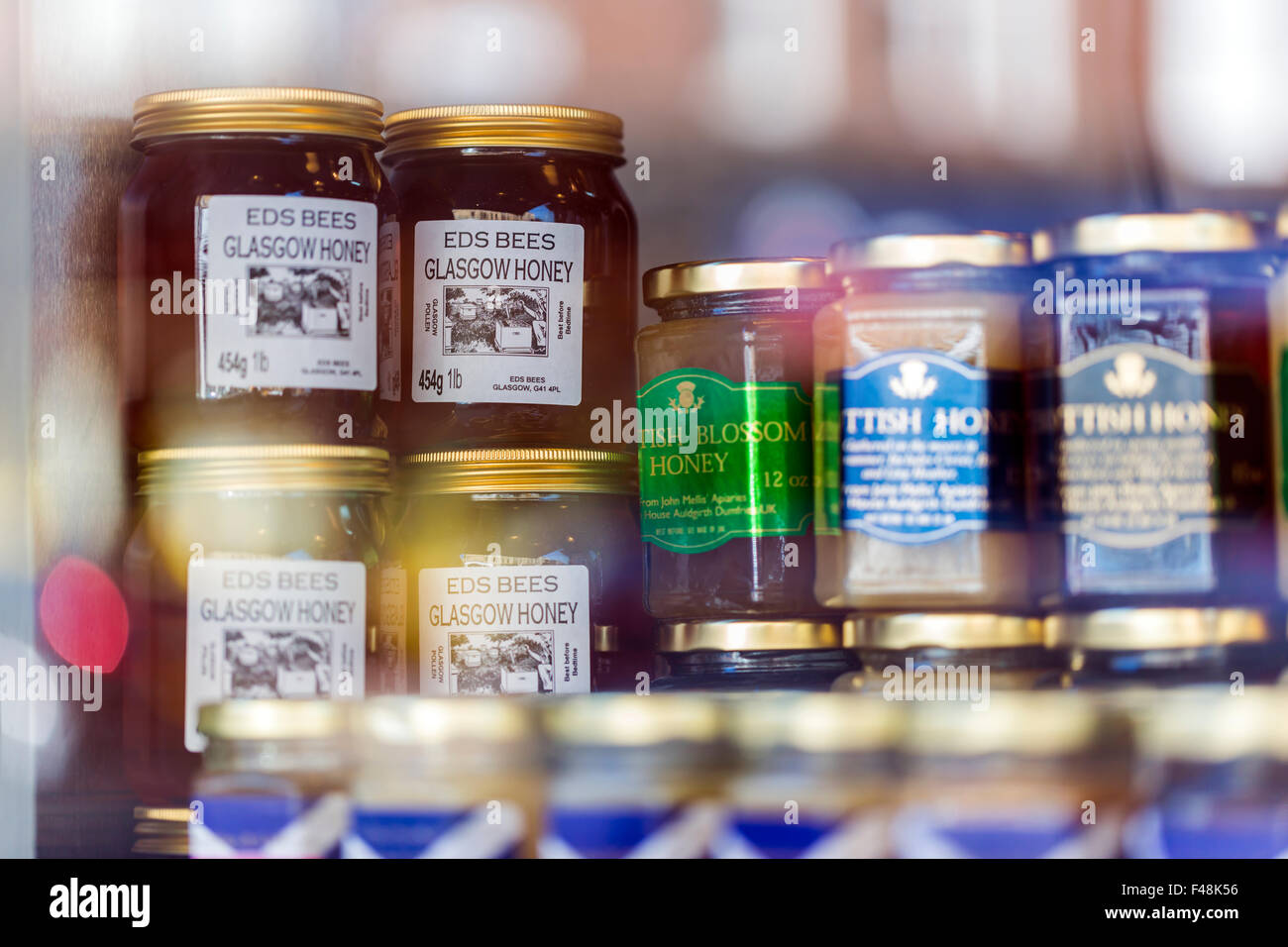 Jars of local honey on display in a shop window, Glasgow, Scotland, UK