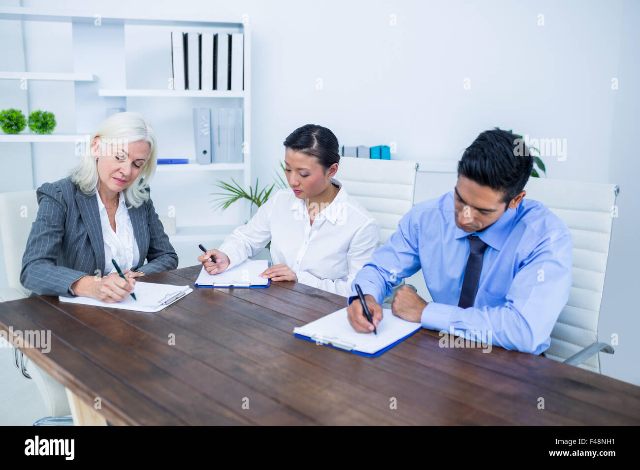 Business people writing on clipboards Stock Photo - Alamy