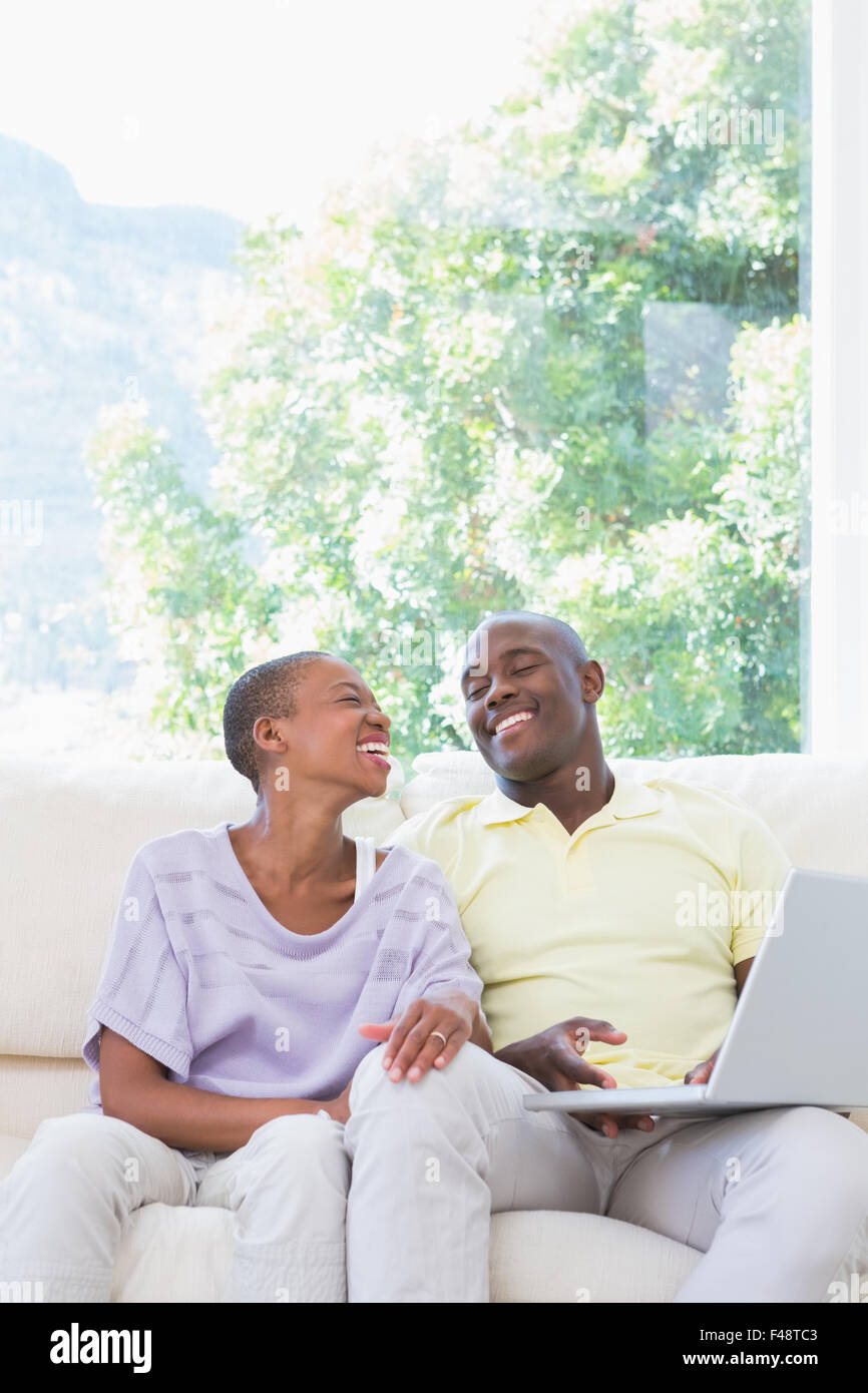 Happy smiling couple using laptop on couch Stock Photo - Alamy