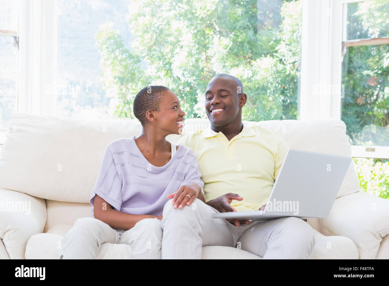 Happy smiling couple using laptop on couch Stock Photo - Alamy
