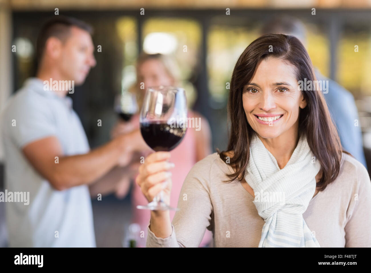 Brunette woman with wineglass in front of group doing wine tasting Stock Photo