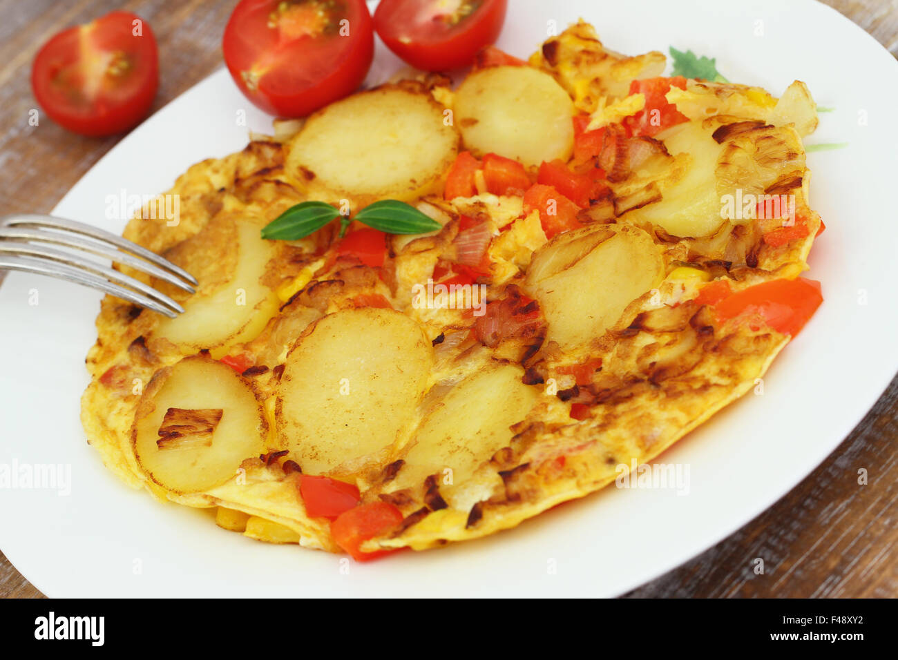 Omelette with potatoes, onions, red pepper and sweetcorn on white plate, closeup Stock Photo