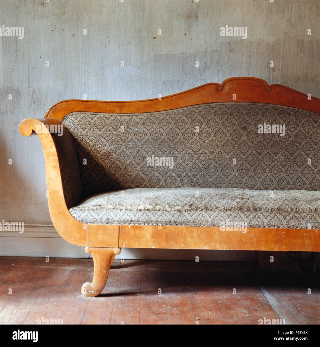 A old divan in front of a worn wall Stock Photo