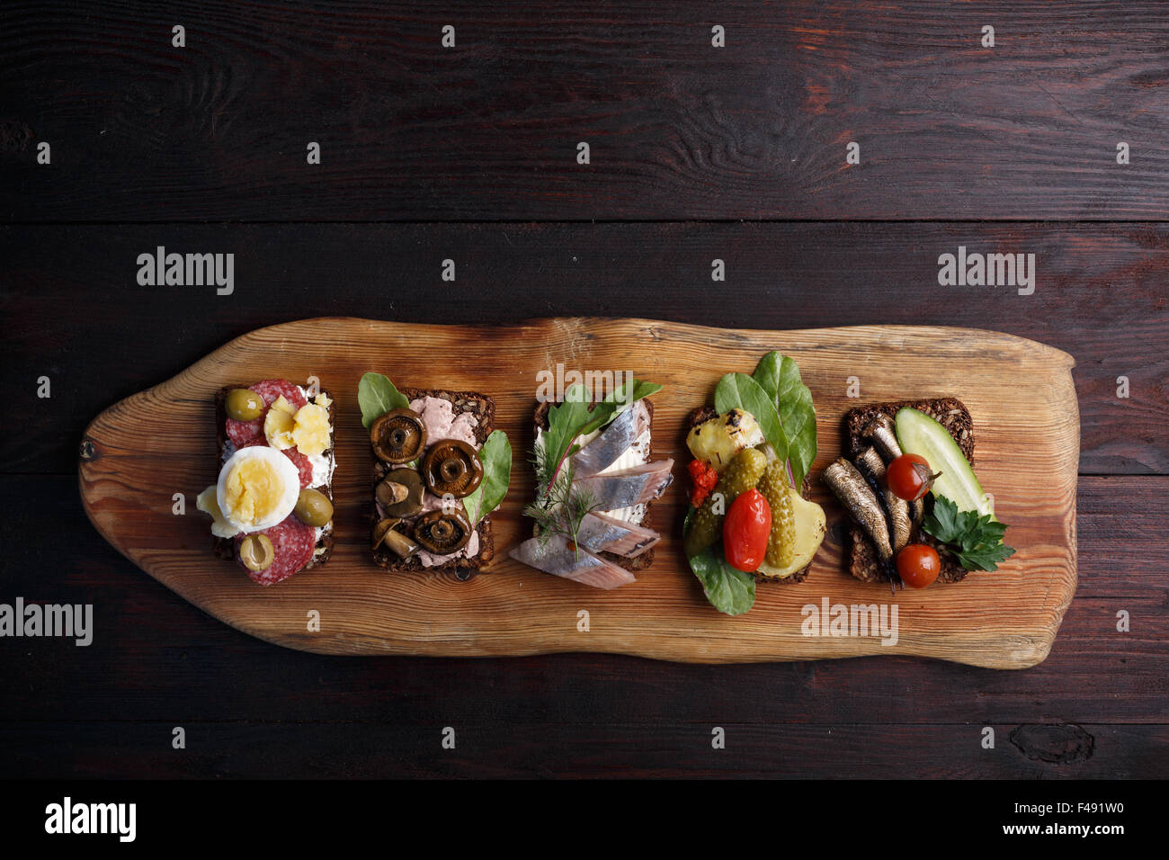 Variety of open sandwiches of buttered dense, dark rye bread with