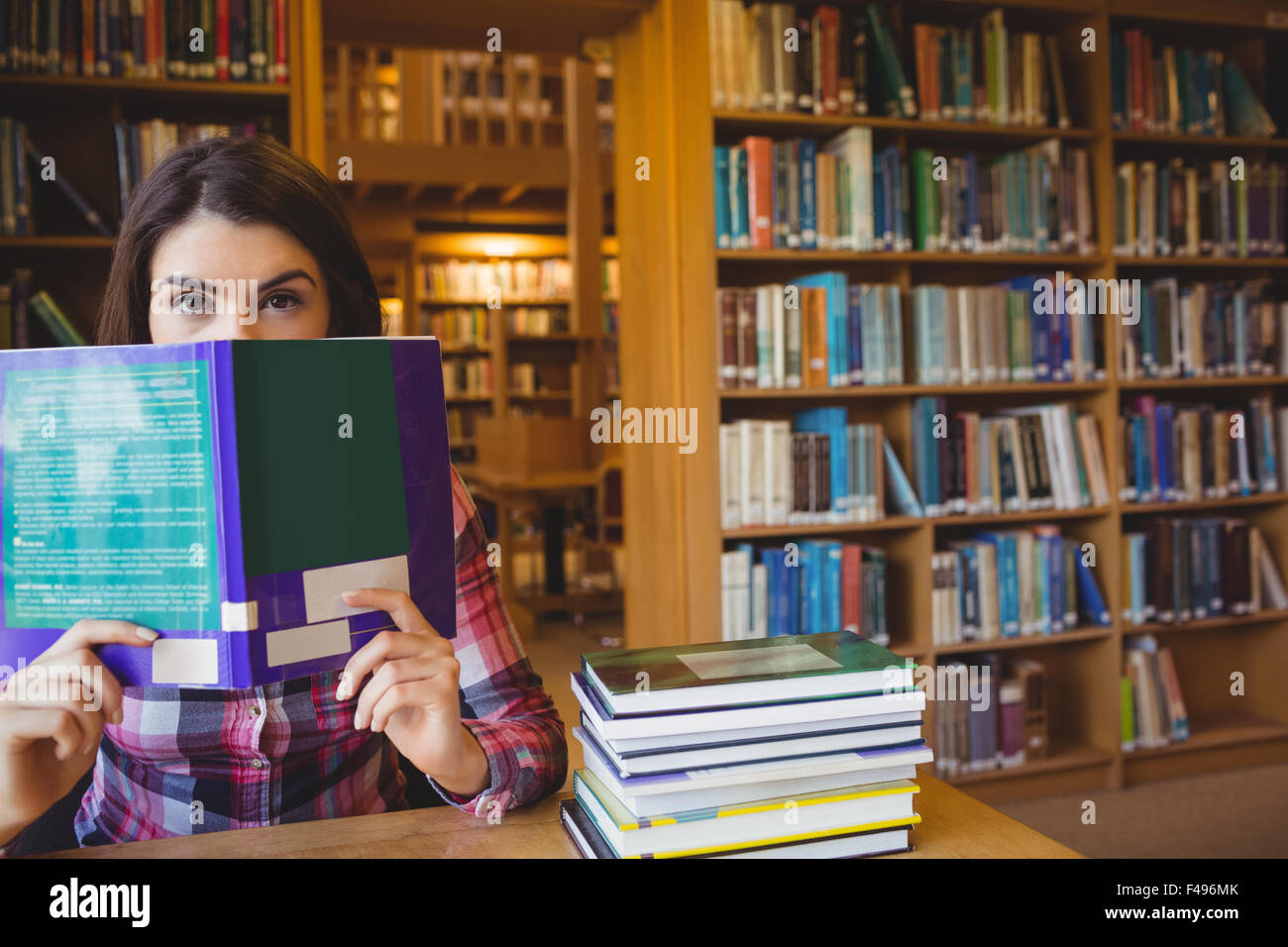 Portrait of female student peeking from book Stock Photo