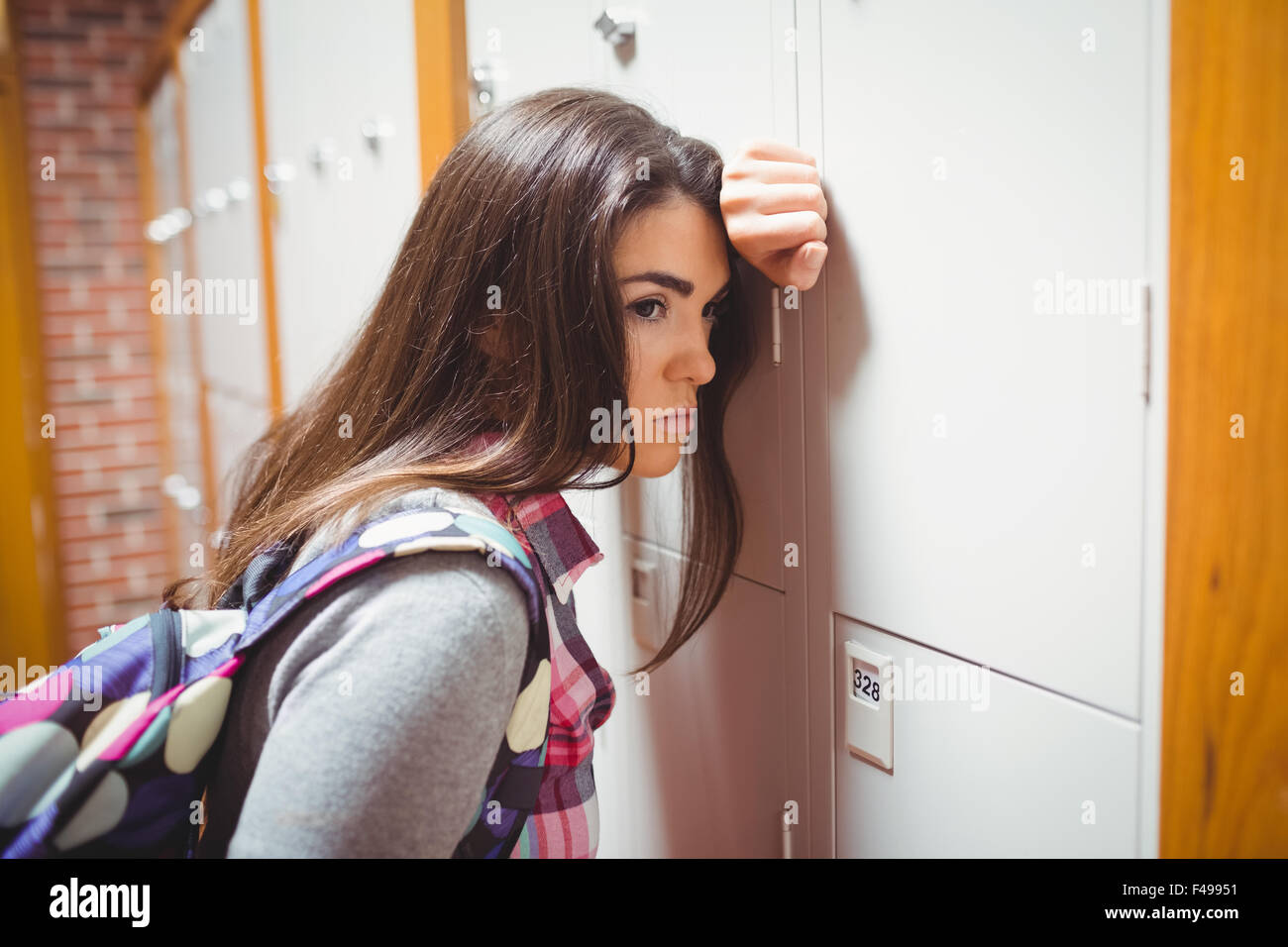 Thoughtful student leaning on locker Stock Photo