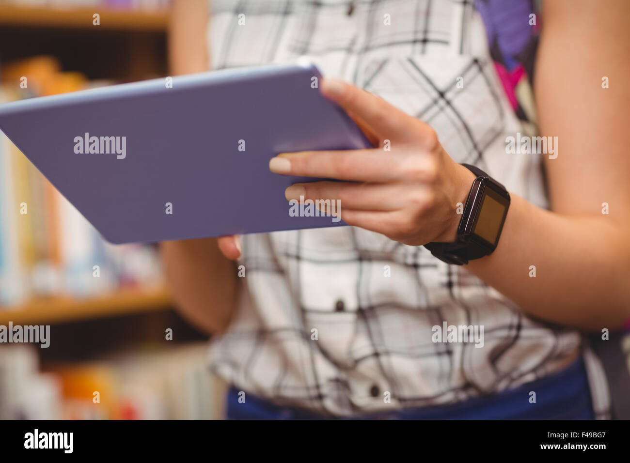 Midsection of student with digital tablet and smart watch Stock Photo