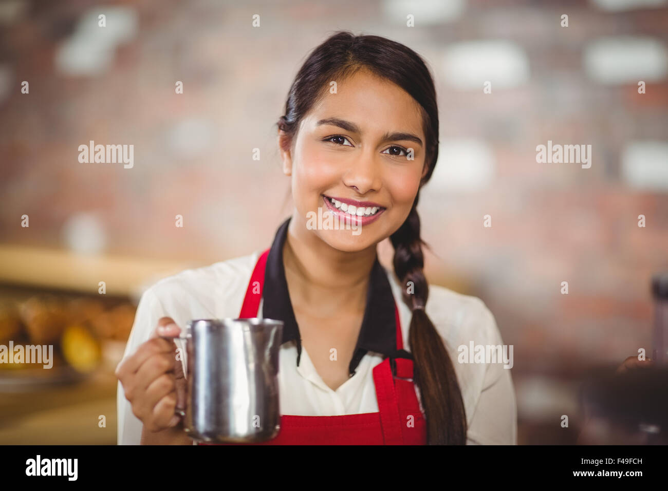 Smiling barista holding a milk jug Stock Photo Alamy