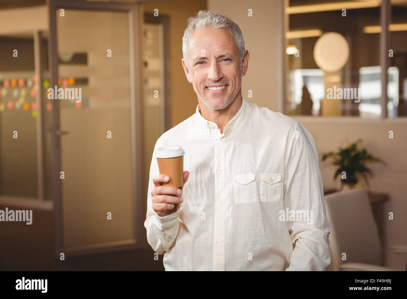 Confident creative businessman holding disposable coffee cup Stock Photo